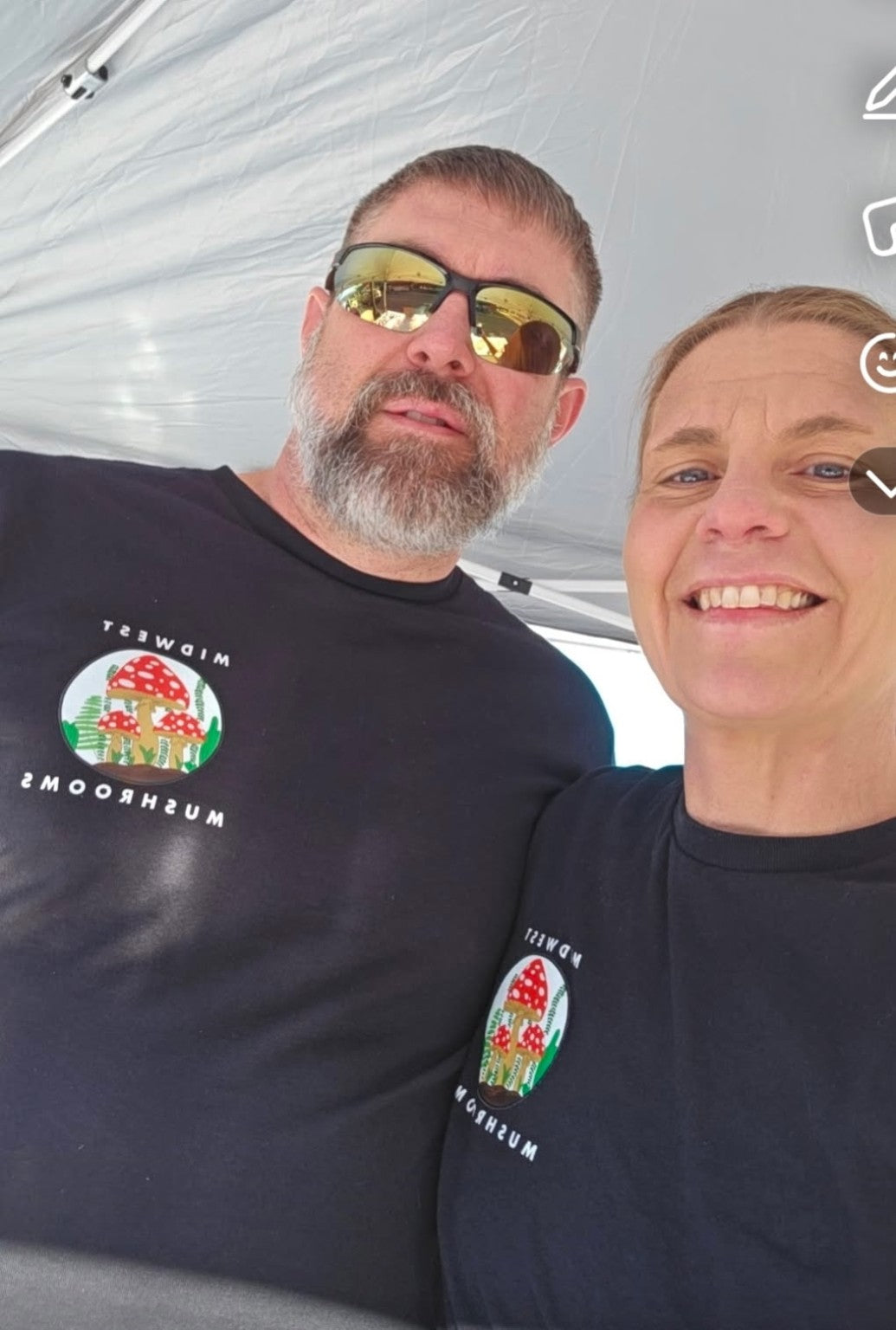 Midwest Mushrooms owners wearing branded shirts at a market